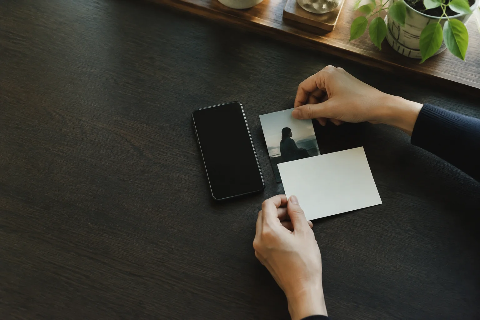 スマートフォンのそばで、ターゲット写真と意図を書くカードを準備する手元